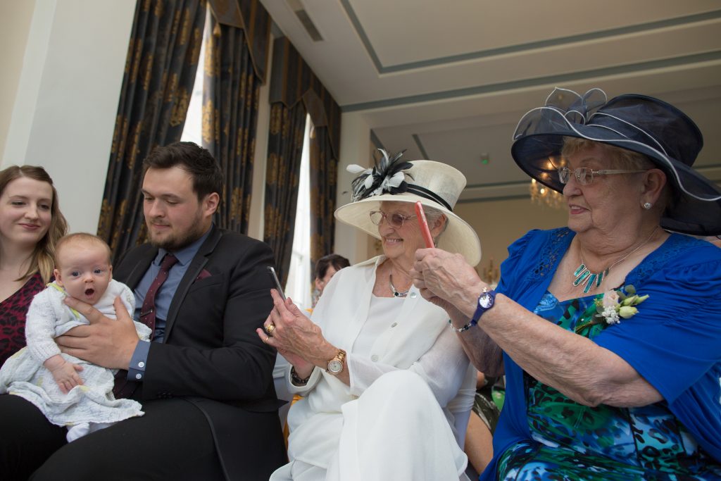 weddings guests taking photo of baby on mobile