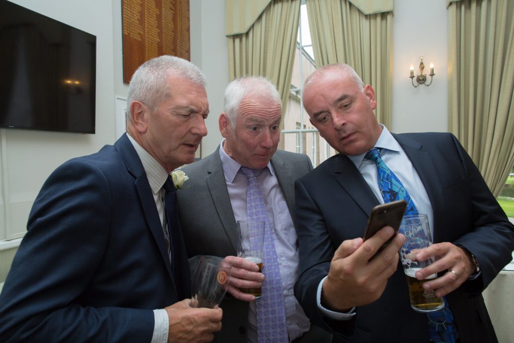 three wedding guests looking at mobile phone