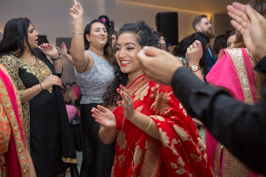 wedding guests wearing red sari dancing