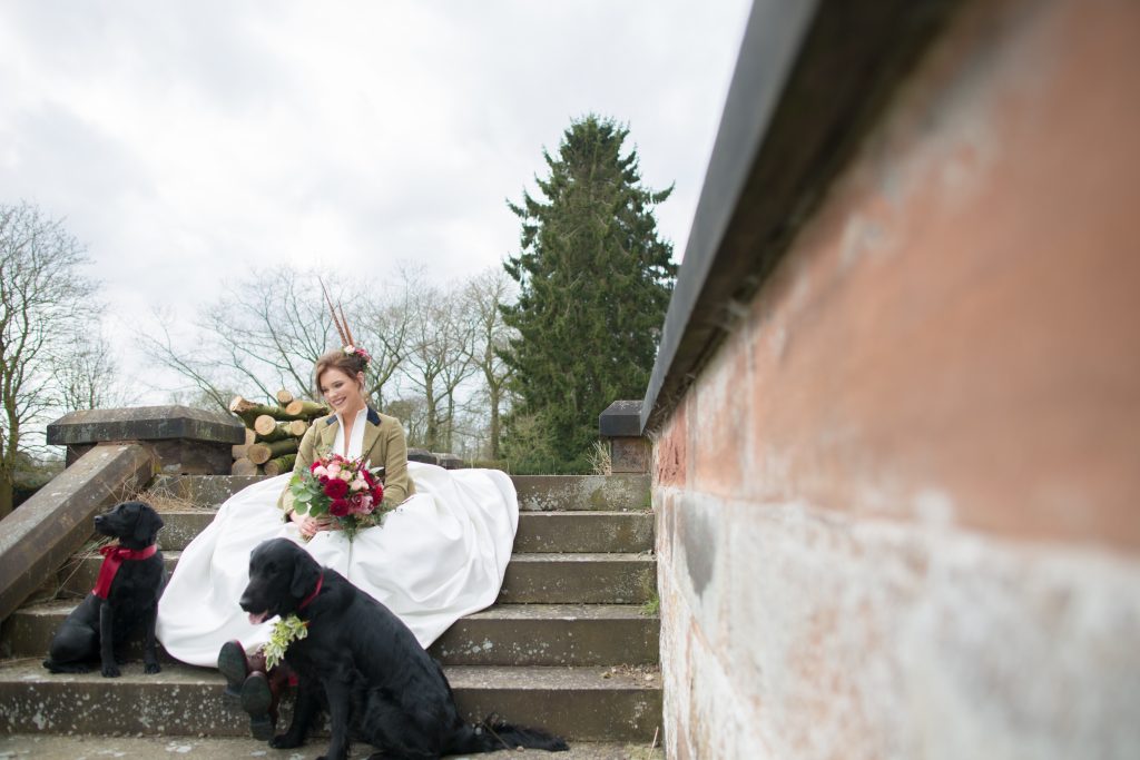 Bride sat on steps with dog at Standon Hall