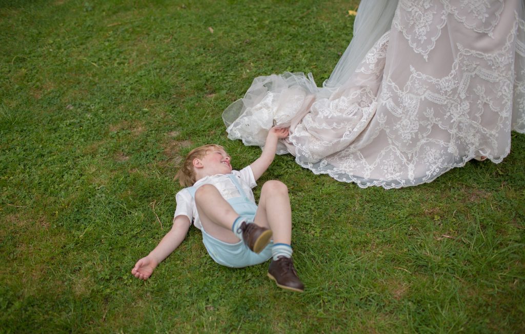 Paige boy lying on grass with wedding dress train