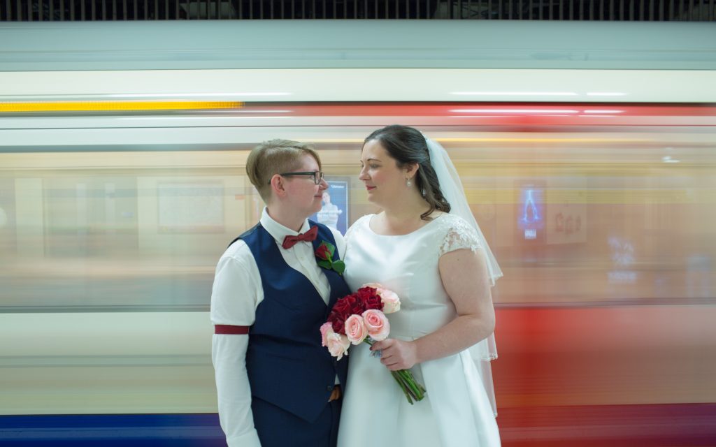 Two brides in London with tube train the background