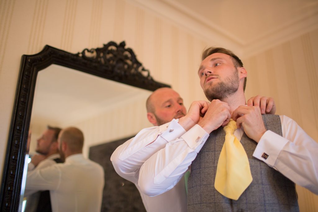 groom having help with tie by best man