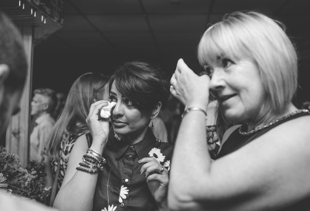 black and white photo of two wedding guests crying