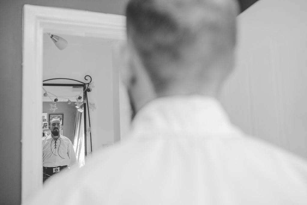 black and white photo of groom looking in mirror