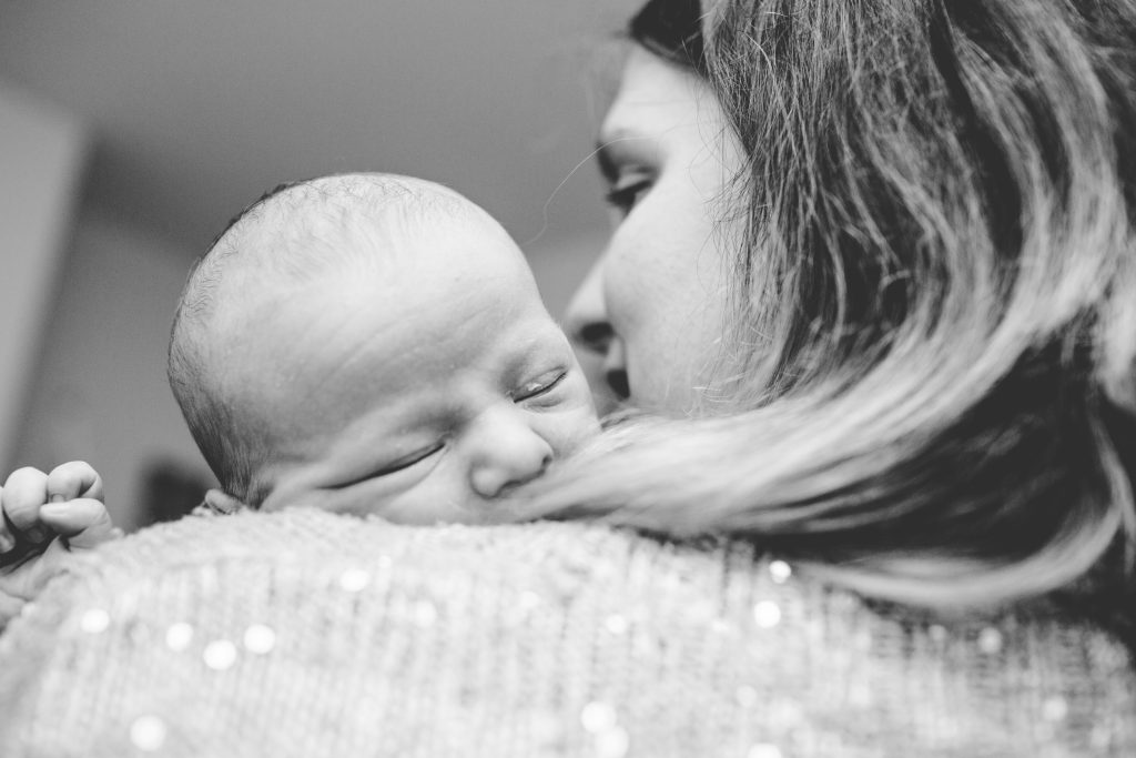 black and white photo of baby over mums shoulder