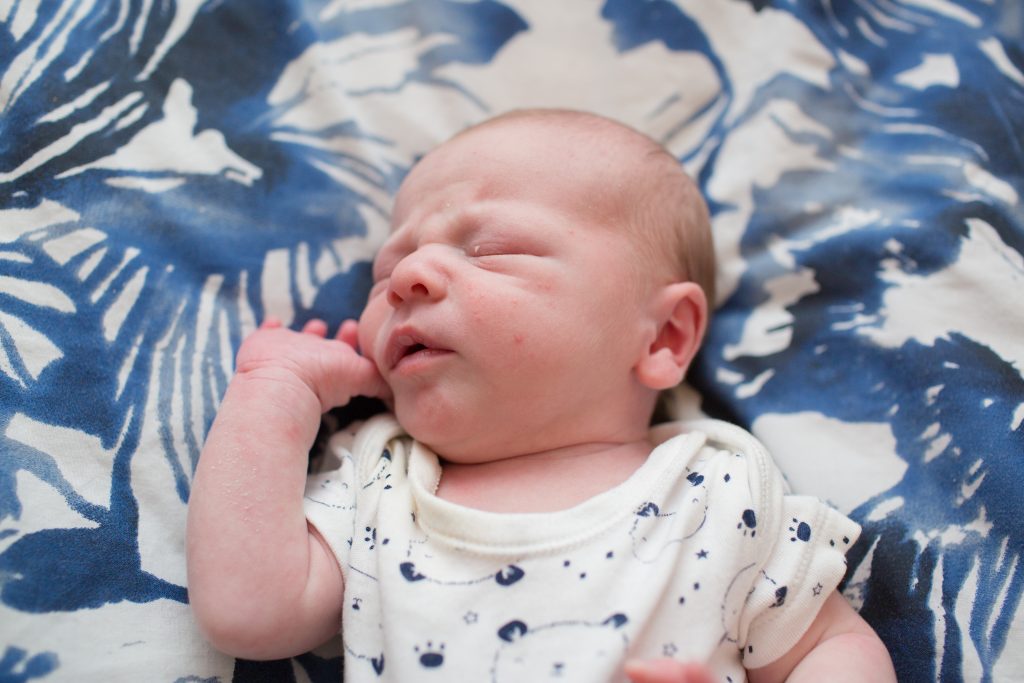 photo of newborn baby lying on bed