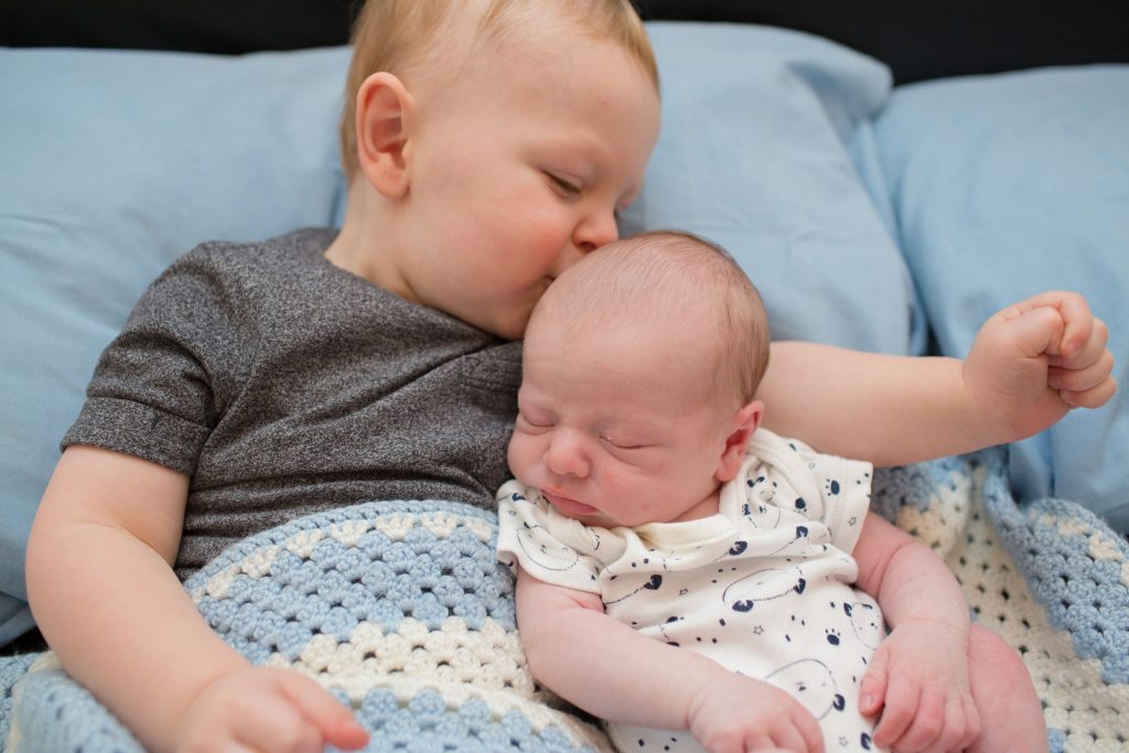 young child kissing baby brother on head