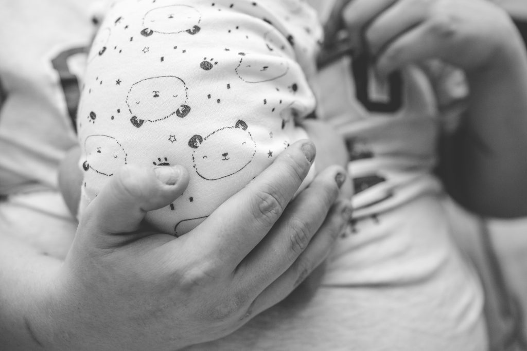 black and white photo of hand holding newborn