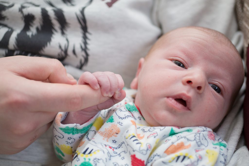 baby holding finger of parent