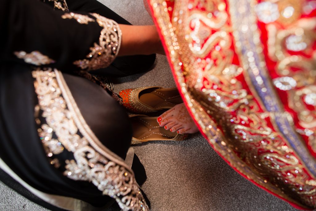 bride having help with wedding shoes