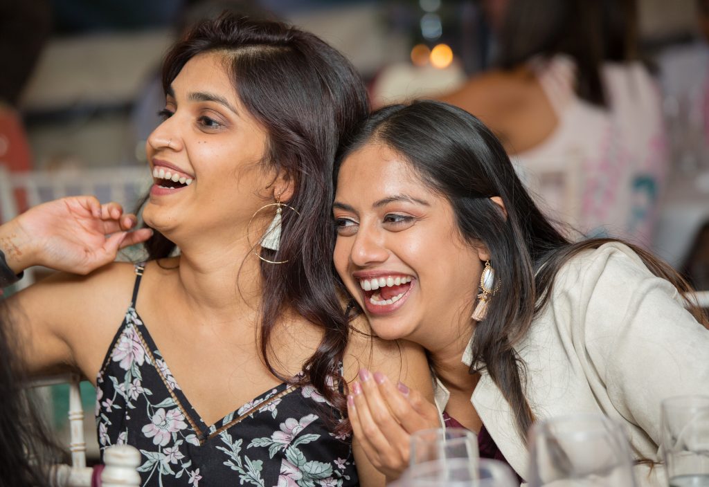 two wedding guests laughing