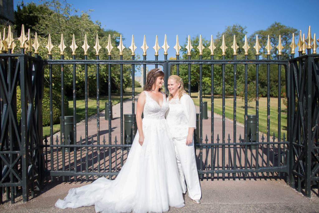 two brides stood in front of gates at windsor castle