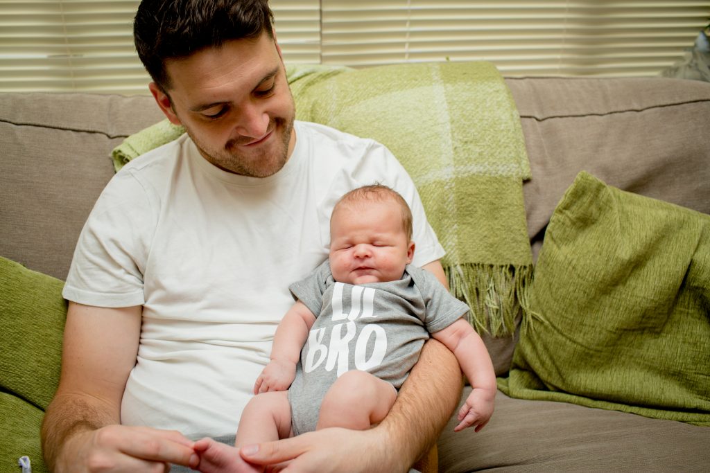 dad smiling holding newborn son