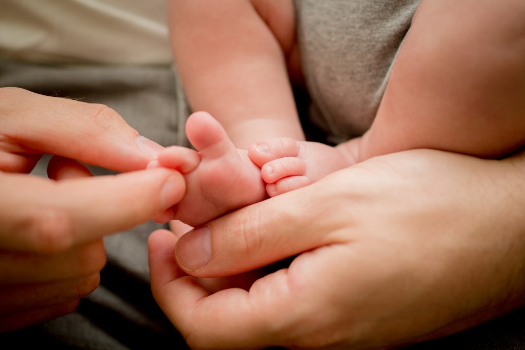 photograph of dads hands holding baby toe