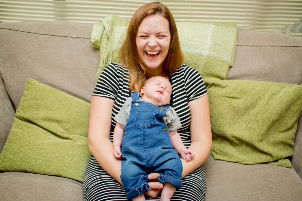 mum laughing holding newborn son