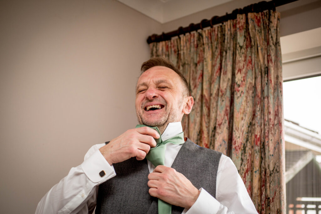 A man trying to tie a knot in a tie on his wedding day