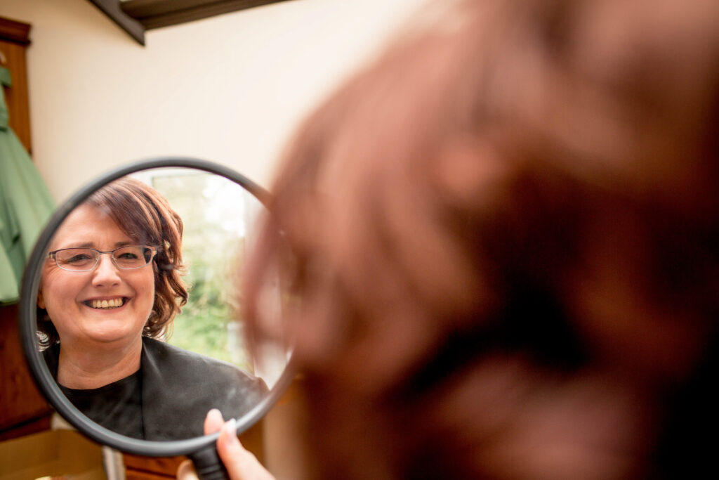 smiling bride looking in a mirror at her wedding make up