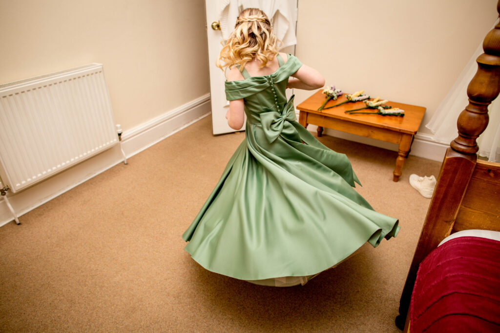 a flower girl in a green dress spinning around