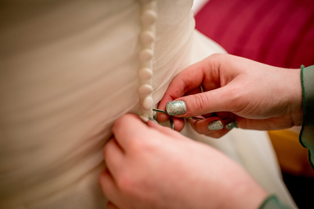 close up photo of wedding dress buttons being done up