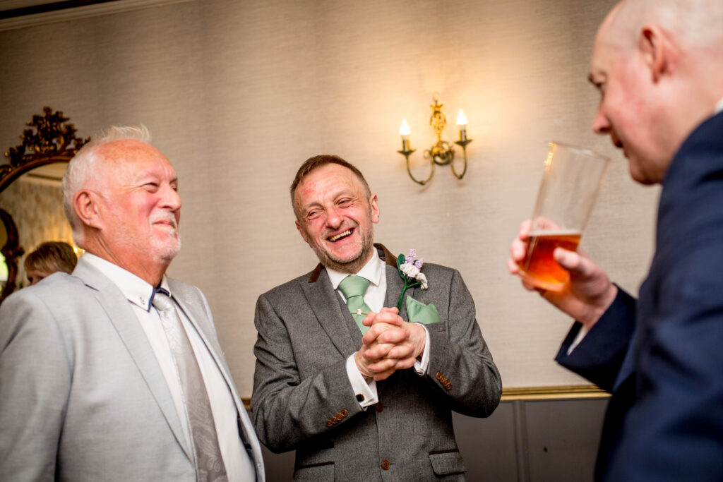 a laughing groom before his wedding with guests