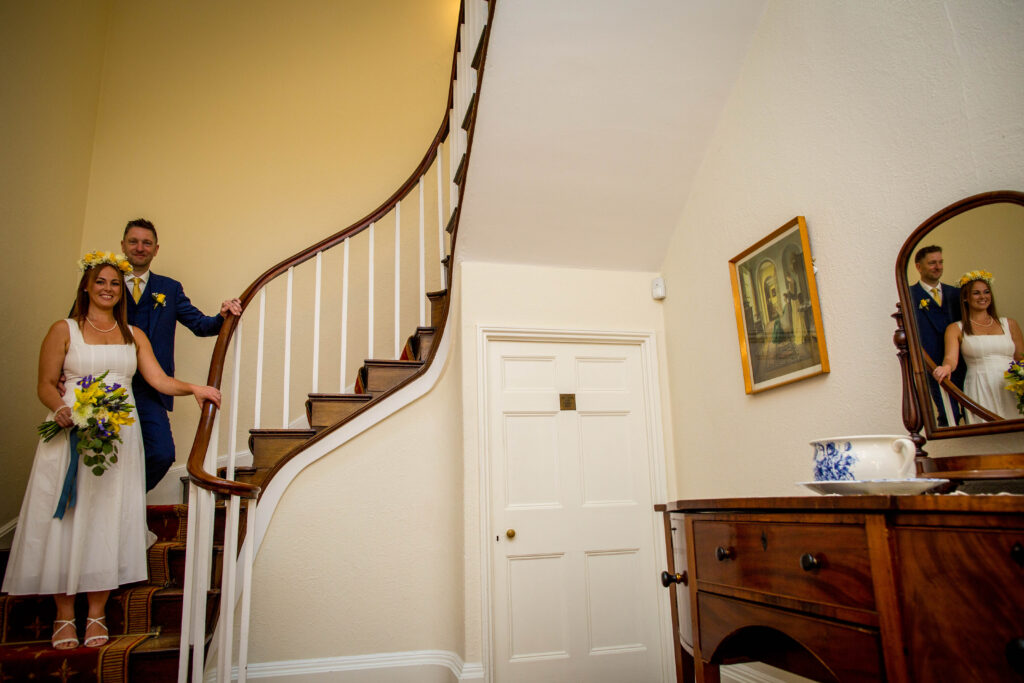 newly married couple stand on stairs in stafford registry office