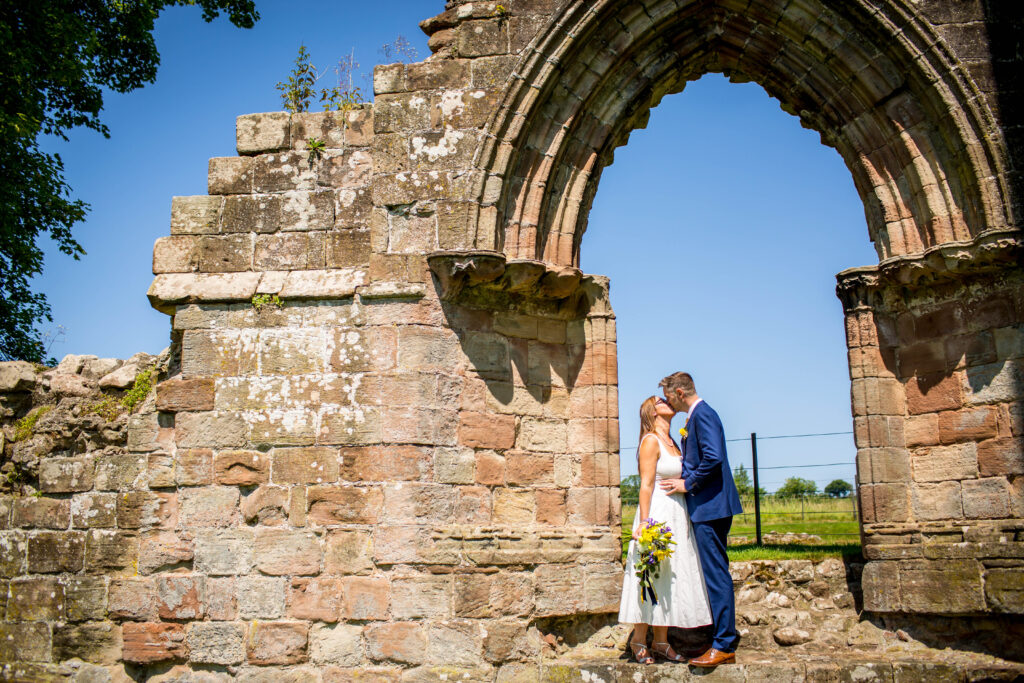 bride and groom stood in an archway ruin of croxden abbey