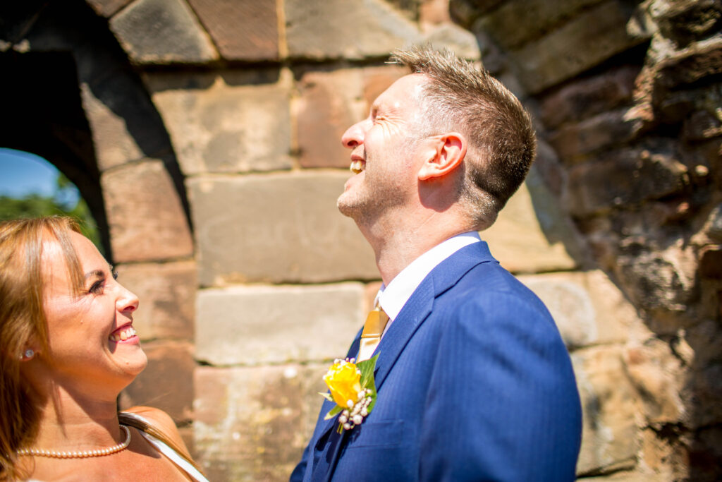 groom in blue suit laughing with bride