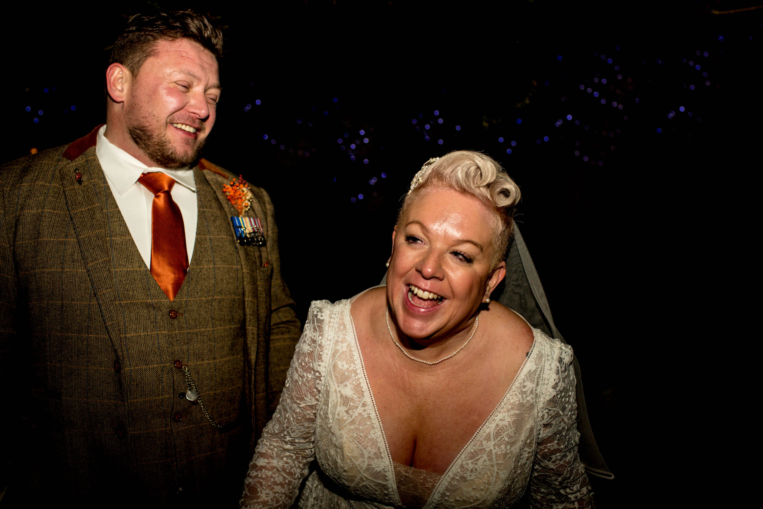 bride laughing leaning forward whilst groom laughs