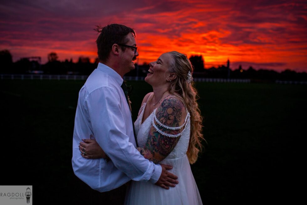 bride and groom looking at each other with sunset in background