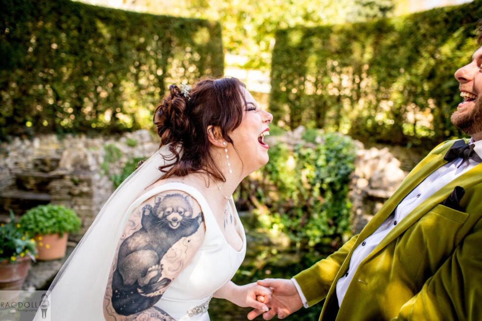 tattooed bride laughing with groom in green velvet jacket